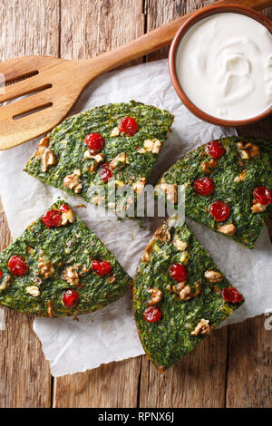 Rustico kuku sabzi frittata di erbe, le uova e i dadi da vicino sul tavolo e yogurt. Verticale in alto vista da sopra Foto Stock