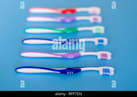 Gli spazzolini da denti su sfondo blu. Piano di composizione dei laici con gli spazzolini manuali. Multi-colore di spazzolini da denti su uno sfondo blu. close up. Foto Stock