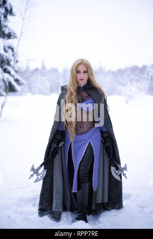 Warrior ragazza con i capelli biondi e big ax nella foresta di inverno Foto Stock