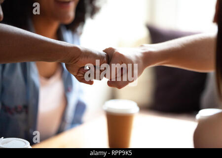 Close up multirazziale amici fist bumping, festeggiare il successo in cafe Foto Stock