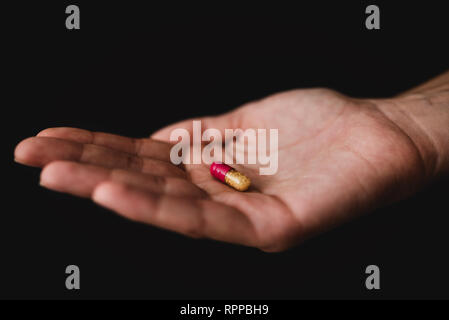 Pillole medicinali in mano, isolati su sfondo nero. Farmacia e medicinali Foto Stock