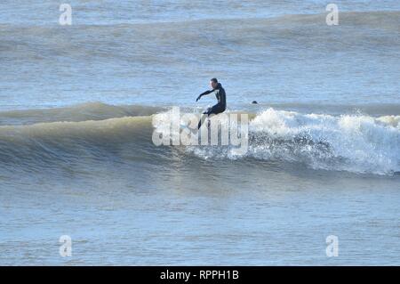 Aberystwyth Wales UK. Venerdì 22 Feb 2019 UK meteo: Surfers godendo incredibilmente caldo sole di febbraio in Aberystwyth sulla costa occidentale del Galles. Il tempo è previsto rimanere bene per i prossimi giorni con la possibilità di registrare le temperature di rottura in alcuni luoghi Photo credit: keith morris/Alamy Live News Foto Stock