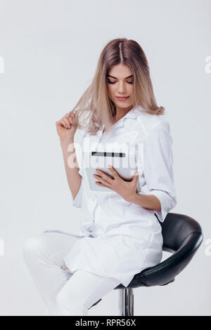 Ritratto di bella bionda medico in camice bianco con tavoletta digitale Foto Stock