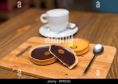 Cioccolato fondente e crostate di limone con cappuccino sul tavolo Foto Stock