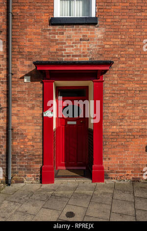 Vista dettagliata del 1950 - 60's Rosso porta anteriore con finestra ovale e portico su un rosso casa in mattoni in luogo di mercato, Tickhill nel Metropolitan Borough di Don Foto Stock