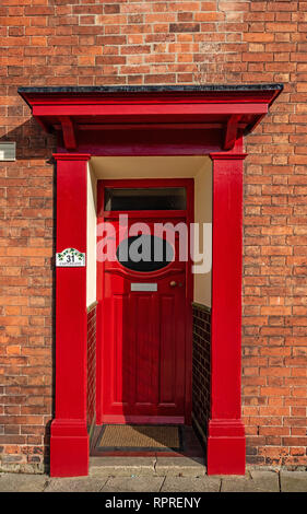 Vista dettagliata del 1950 - 60's Rosso porta anteriore con finestra ovale e portico su un rosso casa in mattoni in luogo di mercato, Tickhill nel Metropolitan Borough di Don Foto Stock