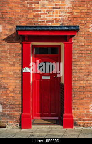 Vista dettagliata del 1950 - 60's Rosso porta anteriore con finestra ovale e portico su un rosso casa in mattoni in luogo di mercato, Tickhill nel Metropolitan Borough di Don Foto Stock