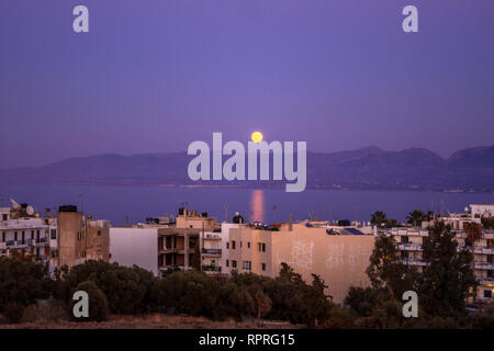 Viola il tramonto sulla baia. Twilight Hersonissos. Full Moon Rising paesaggio. La città di notte. Edifici, il Mar Mediterraneo e le montagne. Isola di Creta. Foto Stock