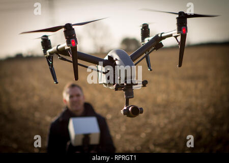 Drone quadcopter con operatore volare al di sopra del raccolto sondaggio conduttore Foto Stock