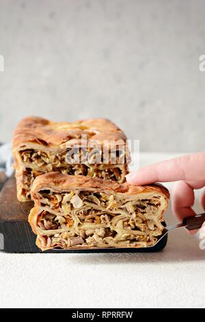 Torta di frittelle con carne e funghi su sfondo grigio. Pancake torta a forma di pane. Cucina slava. Torta di frittelle con carne e funghi su un Foto Stock