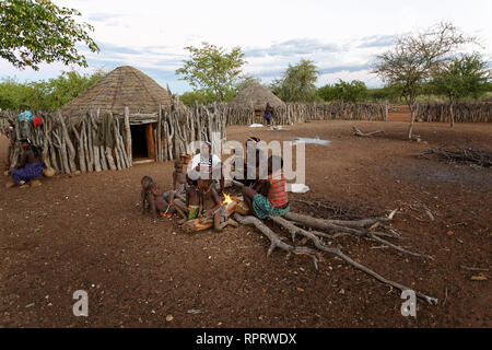 Persone provenienti da tribù Zemba seduti intorno al fuoco in un tradizionale villaggio vicino a Epupa, Namibia, Africa Foto Stock