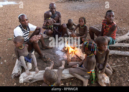 Persone provenienti da tribù Zemba seduti intorno al fuoco in un tradizionale villaggio vicino a Epupa, Namibia, Africa Foto Stock