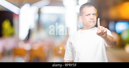 La mezza età uomo arabo wearig t-shirt bianco su sfondo isolato puntando con il dito in alto e espressione arrabbiato Foto Stock