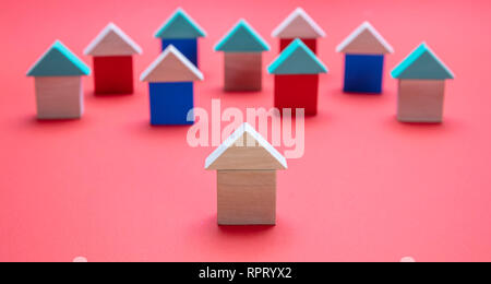 Immobili e di stare fuori concetto, un modello di casa in anticipo sugli altri, rosso colore di sfondo Foto Stock