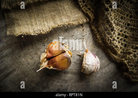 4 spicchi di aglio e il lino naturale igienico sul rustico sfondo di legno Foto Stock