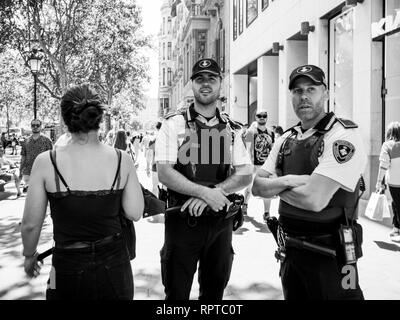 Barcellona, Spagna - 1 GIU 2018: gli ufficiali di polizia sorvegliare persone su strada la folla in Barcellona centrale boulevard europeo di centinaia di persone il pendolarismo su una calda giornata di lavoro home visita città - in bianco e nero Foto Stock