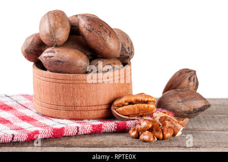 Noci pecan in una ciotola di legno sulla vecchia scheda con sfondo bianco Foto Stock