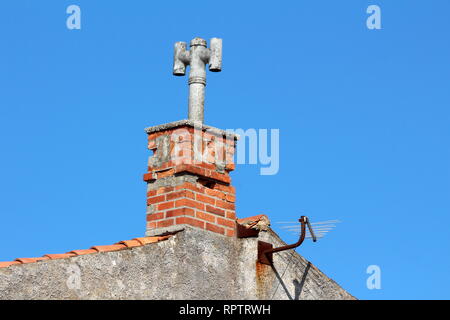 Casa Famiglia camino con calcestruzzo top in forma chiusa del tubo di calcestruzzo con due tubi aggiuntivi su entrambi i lati e la piccola antenna TV Foto Stock