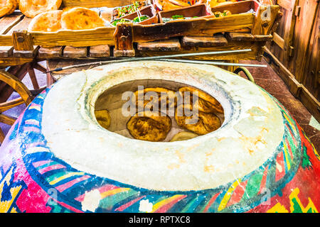 Fatto in casa pane lavash essendo cotti all'interno di un tradizionale pavimento armeno forno chiamato tonir Foto Stock