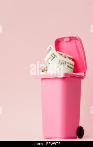 Di dollari di banconote in rosa spazzatura su sfondo rosa. Foto Stock