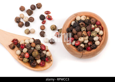 Miscela di peperoni calda, rosso, nero, bianco e pepe verde in una ciotola di legno e cucchiaio isolati su sfondo bianco Foto Stock