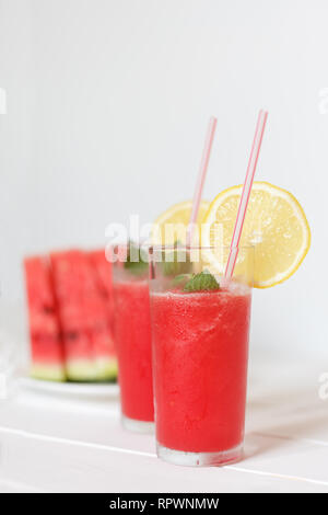 Due bicchieri con cocomero frullati con limone e menta su sfondo rustico Foto Stock