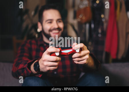 Ritratto di un giovane uomo di videogiochi, riproduzione di video giochi, vincere e festeggiare. Focus sul joystick. Foto Stock