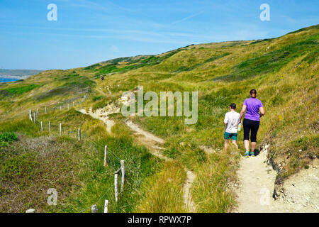 La gente camminare lungo il sentiero costiero attraverso Durlston Country Park e riserva naturale nazionale, Swanage, Dorset, Regno Unito. Isola di Purbeck Foto Stock