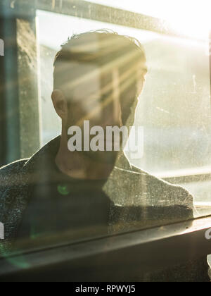Un uomo bello dietro il vetro all'aperto nella cabina di telefono Foto Stock