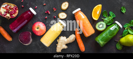 Vari frullati colorati o di succhi di frutta in bottiglie e ingredienti sul buio. Una sana dieta vegana detox alimenti puliti concetto, vista dall'alto, banner. Foto Stock