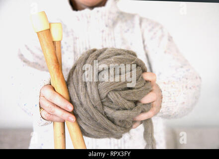 Donna che mantiene un gomitolo di lana e aghi di tessitura Foto Stock