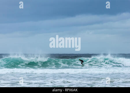 Surfista maschio in muta a cavallo di un onda sulla spiaggia Dalmore, isola di Lewis, Ebridi Esterne, Scozia Foto Stock