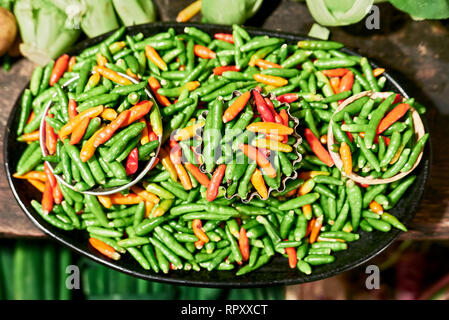 Close-up di abbondanza piccolo verde e il peperoncino rosso posto su una piastra con piccoli pronto ad acquistare porzioni, in vendita in Chinatown, Manila, Filippine Foto Stock