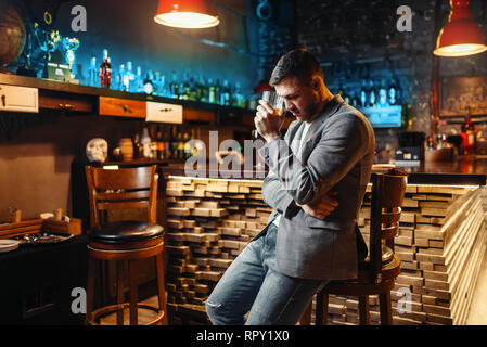 Triste uomo con bicchiere di bevanda alcolica al bar in legno contatore. Stanco cliente in pub, maschio persona potrete rilassarvi nel ristorante Foto Stock