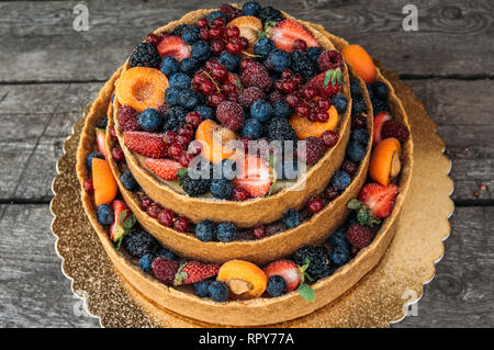 Primo piano della cheesecake con frutti e bacche sul vecchio tavoloni Foto Stock