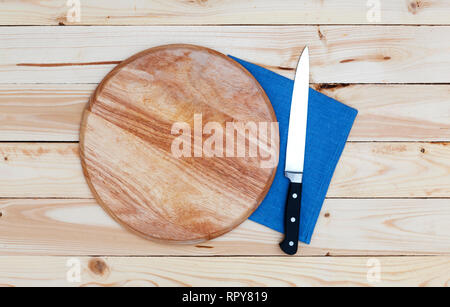 Round tagliere con un coltello su un tavolo di legno, vista dall'alto Foto Stock