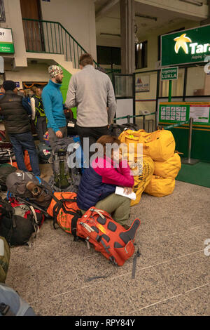 Il Nepal, Kathmandu, l'aeroporto internazionale di Tribhuvan, domestici area di partenza, i passeggeri seduti sui bagagli in attesa per i voli in ritardo a Lukla Foto Stock