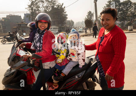 Il Nepal, Kathmandu, Thamel, Swayambhu Marg, donna portante due giovani bambini su moto, fuori Indrani e templi Mahadev Foto Stock