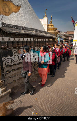 Il Nepal, Kathmandu, Swayambhunath Temple, gruppo di scuola nepalese bambini la filatura ruote della preghiera Foto Stock