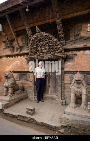 Il Nepal, Kathmandu, centro città, Jyatha Marg, Chhusya Bahal, senior maschile di seguito turistico antica torana scolpita sopra la porta del tempio Foto Stock