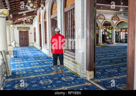 Adoratore pregando nel corridoio principale sala di preghiera di Kampung Kling moschea, Masjid Kampung Kling, Melaka, Malaysia. Foto Stock