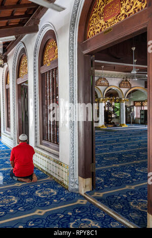 Adoratore pregando nel corridoio principale sala di preghiera di Kampung Kling moschea, Masjid Kampung Kling, Melaka, Malaysia. Foto Stock