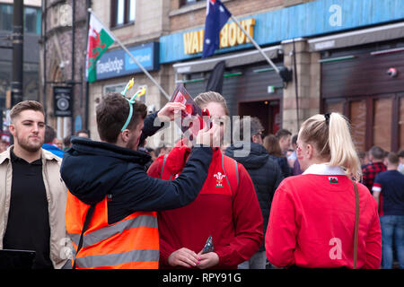 CARDIFF, Regno Unito. Il 23 febbraio 2019. Due Welsh rugby fan di ottenere il loro volto dipinto nel centro di Cardiff prima dell'Inghilterra e Galles corrispondono Foto Stock