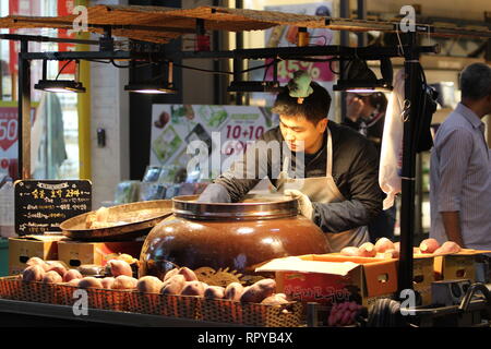 Myeong-Dong, / Seoul COREA DEL SUD - 1 Aprile 2018: come la notte si avvicina, una cucina di strada venditore pulisce la sua giara. Foto Stock