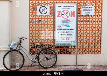 Bicicletta parcheggiata di fronte nessun segno di parcheggio. Vietato fumare vieta di fumare nell'Area del patrimonio. Malacca, Malaysia. Foto Stock