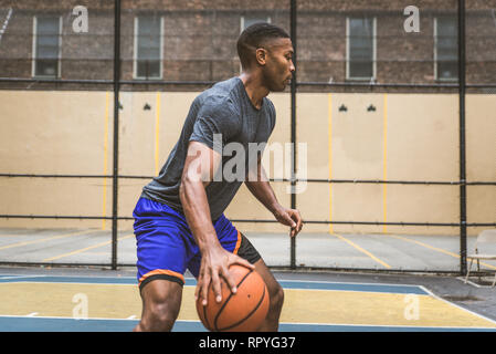 Afro-americane del giocatore di basket sulla formazione di una corte di New York - uomo sportivo giocando a basket all'aperto Foto Stock