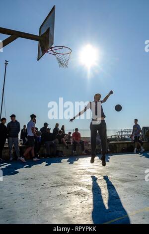 Brighton, Sussex, Regno Unito. Il 23 febbraio, 2019. Persone giocare a basket sulla spiaggia tribunali in Brighton nella luminosa primavera-estate come inverno sun su Sabato, Feb 23, 2019 . Credito: Julie Edwards/Alamy Live News Foto Stock