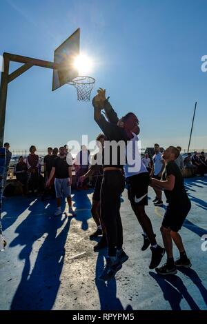 Brighton, Sussex, Regno Unito. Il 23 febbraio, 2019. Persone giocare a basket sulla spiaggia tribunali in Brighton nella luminosa primavera-estate come inverno sun su Sabato, Feb 23, 2019 . Credito: Julie Edwards/Alamy Live News Foto Stock