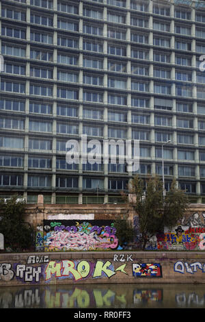 Creative graffiti in contrasto con architettura urbana sul canale del Danubio, a Vienna, in Austria Foto Stock