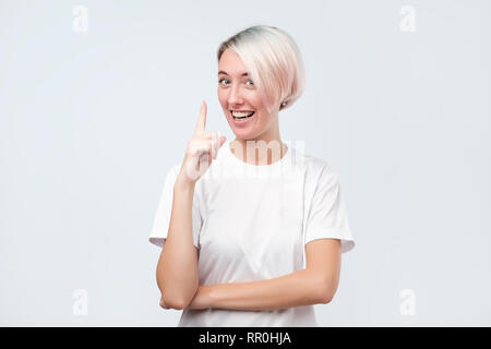 Sorridente ragazza piuttosto puntare il dito indice fino dare consigli. Foto Stock